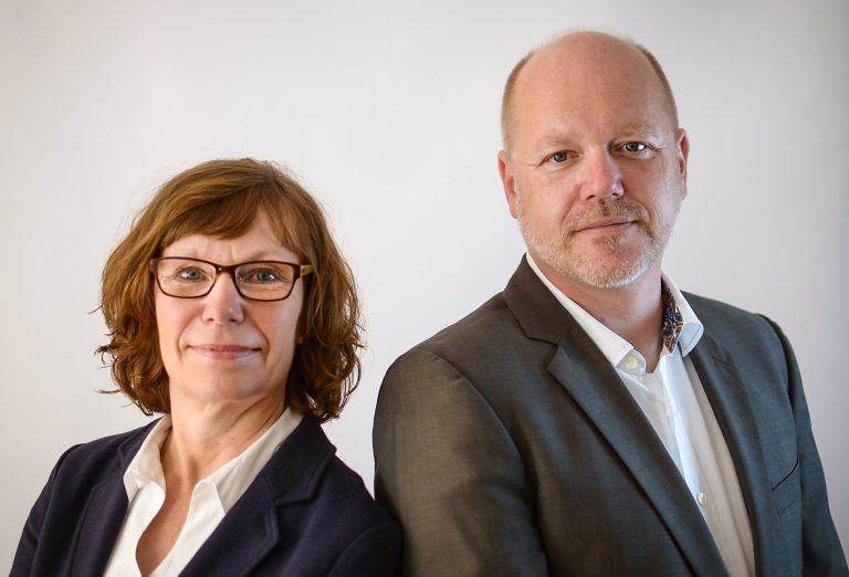 Porträt von zwei Personen, einer Frau und einem Mann, beide professionell gekleidet.