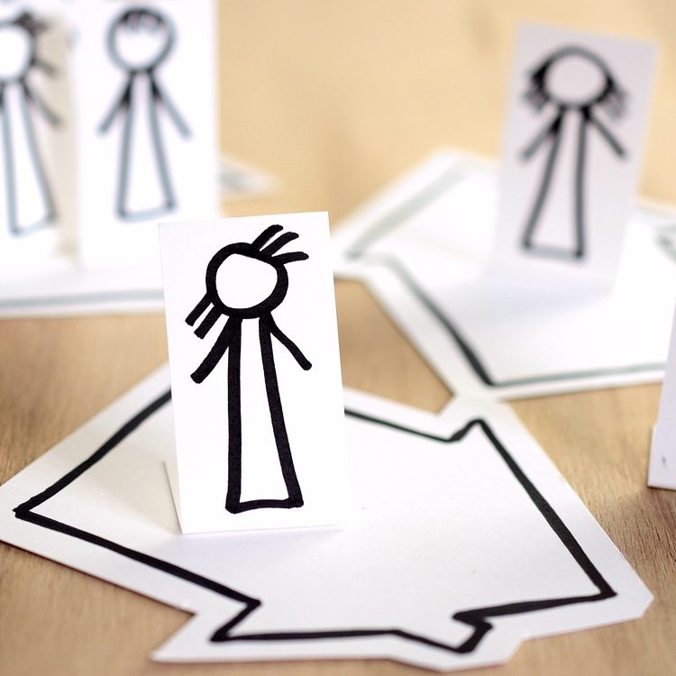 Bunte Papierschnitte von Personen auf grafischen Pfeilen angeordnet.